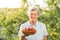 Happy senior caucasian woman picking up strawberries in the garden during the sunset or sunrise. Elderly lady farmer with grey