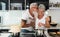 Happy senior couple having fun cooking together at home - Elderly people preparing health lunch in modern kitchen