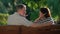 Happy senior couple laughing and joking on bench at park.