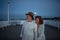 Happy senior couple in love on walk holding hands outdoors on pier by sea at moonlight, looking at view.