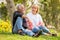 Happy senior couple relaxing at park together in morning time. old people sitting on grass in the autumn park . Elderly resting .