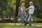 Happy senior couple relaxing at park  walking with bike and talking  together in morning time. old people in the autumn park .