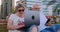 Happy senior couple sitting on a bench in the summer in a modern city with a laptop on the background of skyscrapers