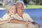 Happy Senior Couple Sitting On Park Bench Laughing