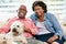 Happy Senior Couple Sitting On Sofa With Dog