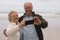 Happy senior couple taking selfie with mobile phone at the beach