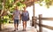 Happy senior couple walking holding hand at Koh Phangan beach promenade - Active elderly and travel lifestyle concept