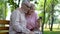 Happy senior couple watching smartphone photos, retirement leisure in park