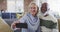 Happy senior diverse couple in living room sitting on sofa, using smartphone, making video call