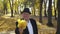 Happy senior dressed in a suit and hat shows maple leaves' bouquet at camera