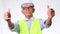 Happy senior engineering architect wearing a vest and helmet shows thumbs up on a white background in studio.