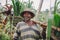 Happy senior farmer carrying a yoke on his shoulders