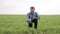 a happy Senior farmer kneels in the green wheat field, touches the wheat with his hand,