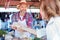 Happy senior farmer standing behind market stall, selling organic vegetables