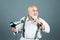 Happy senior hairdresser barber with hair dryer and comb drying beard and moustache. Portrait of old barber holding