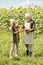 Happy senior male farmer in workwear passing bottle of sunflower oil to female