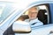 Happy senior man driving car with open window