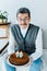 Happy senior man holding birthday cake while sitting on sofa a in