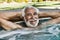 Happy senior man relaxing at the edge of swimming pool