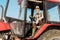 happy senior self-employed farmer in straw hat driving tractor.