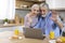 Happy senior spouses making video call with laptop in kitchen during breakfast