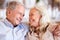 Happy senior white couple sit at home embracing, smiling at each other, head and shoulders, close up