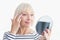 Happy senior woman applying eye anti-wrinkle cream