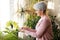 Happy senior woman cleaning houseplant