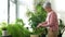 Happy senior woman cleaning houseplant