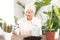 Happy senior woman cultivating potted plants at home