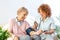 Happy senior woman having her blood pressure measured in a nursing home by her caregiver. Happy nurse measuring blood pressure of