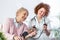 Happy senior woman having her blood pressure measured in a nursing home by her caregiver. Happy nurse measuring blood pressure of