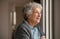 Happy senior woman looking out of the window at home