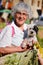 Happy senior woman in the mountain with bouquet of forest flowers and her dog