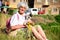 Happy senior woman in the mountain with bouquet of forest flowers and her dog