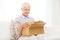 Happy senior woman with parcel box at home