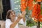 Happy senior woman relaxing with red jade vine flowers on terrace at home