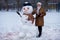 Happy senior woman sculpt a big snowman in winter