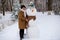 Happy senior woman sculpt and hug a big real snowman in winter
