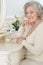 Happy senior woman sitting near dressing table