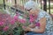 Happy senior woman smelling and touching perple flowers at summer garden