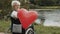 Happy senior woman in the wheelchair near the river offering a balloon heart with a smile. Love and care concept