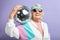 Happy senior woman in white sportswear holding discoball in hands on purple