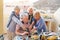 Happy seniors watching on mobile smart phone at dinner on terrace - Retired people having fun dining together