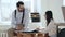 Happy serious young CEO businessman talking to beautiful female colleague sitting on table at modern comfortable office.