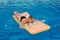 Happy seven year old boy lying on air mattress in outdoor pool