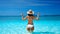 Happy sexy woman in white bikini and straw hat showing peace sign with both hands relax in turquoise sea