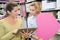 Happy shop assistant with tablet pc helping woman