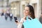 Happy shopper holding phone and shopping bags