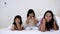 Happy sibling girls playing peekaboo game with her mother in white blanket on the bed. Family and happy moments concept.